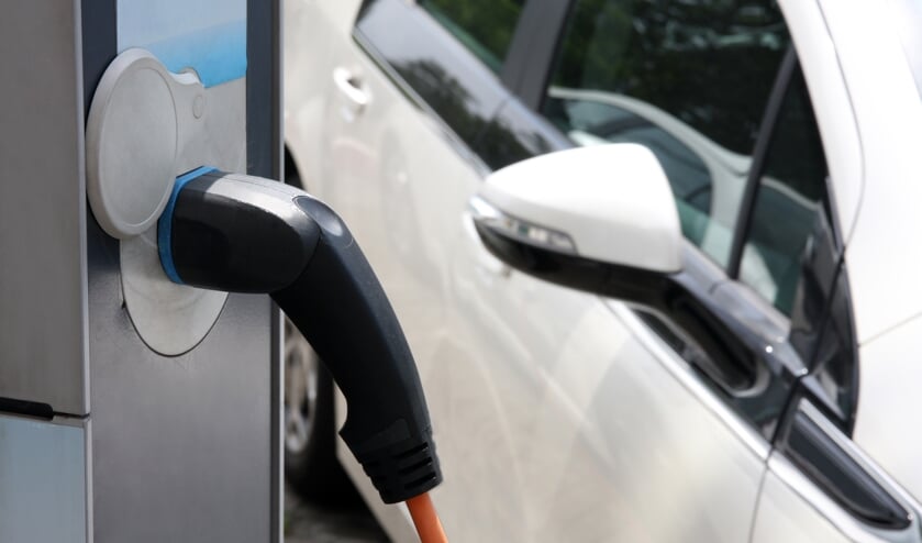 <p>Electric car being charged at the station, close up of the power supply plugged</p>