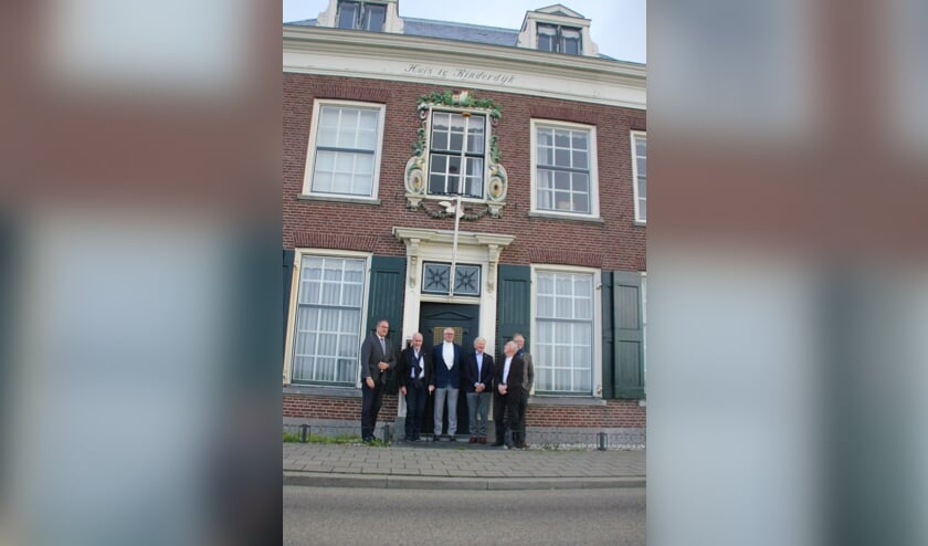 • Het stichtingbestuur met burgemeester Paans en kunstenaar Roel Teeuwen bij Huis te Kinderdijk, met het beeldje van Beatrijs in de gevel.