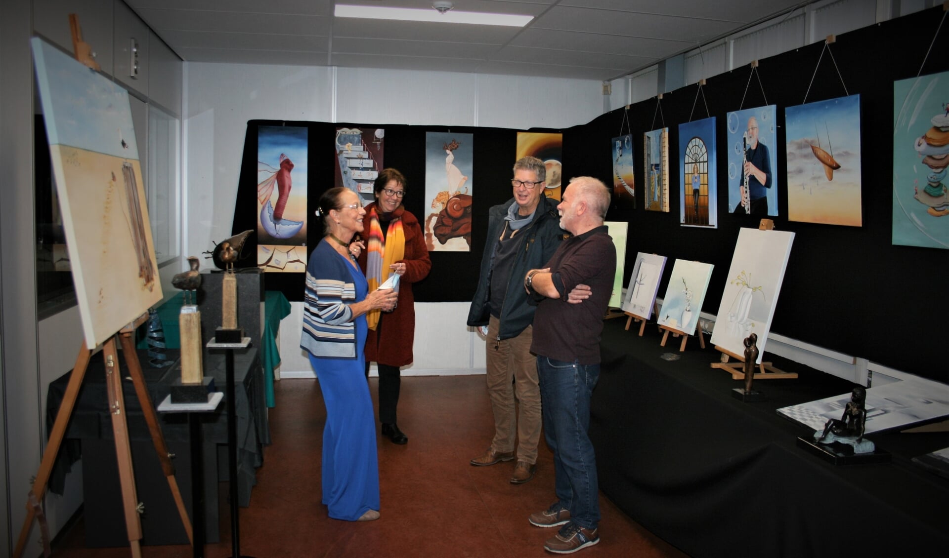 Corry Henning-Snel praat, te midden van haar werk, met collega-kunstenaar Eef van Toorn (rechts) en een tweetal bezoekers.