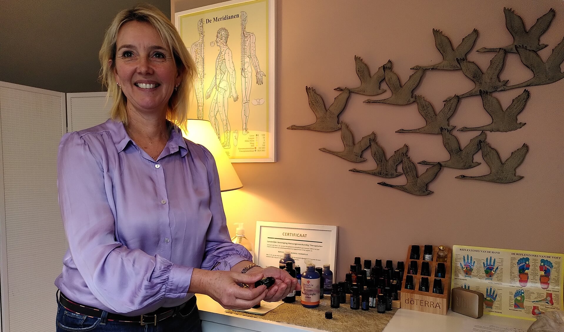 Massage- en aromatherapeut Marjolijn van der Wal met haar collectie oliën.