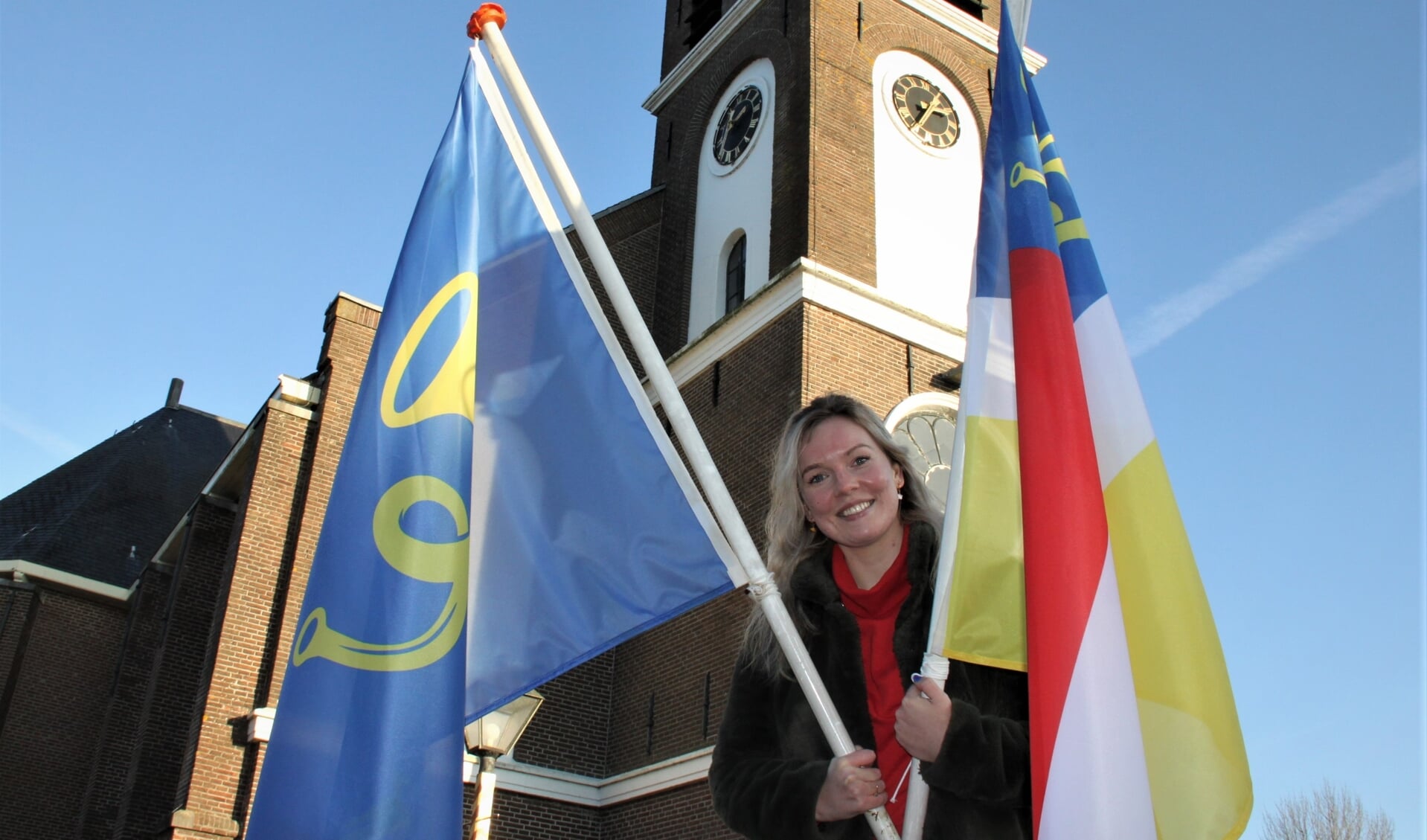 • Mijntjes de Leeuw met de twee dorpsvlaggen van Zegveld. De blauwe vlag heeft ze zelf ontworpen.