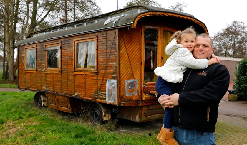 • Piet van Assendorp en zijn kleindochter Sophie voor de 'opknapwoonwagen' aan de ingang van het Arkelse woonwagenkamp.  