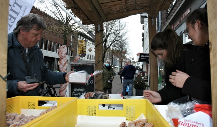<p>Wout Peters uit Tiel neemt zijn oliebollen in ontvangst van Mirthe en Danique (rechts).</p>