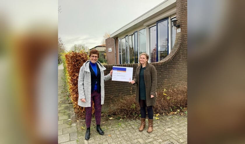• De overhandiging van de cheque, met links Corrie de Kluijver van de Rabobank en rechts Anita de Vroom.  