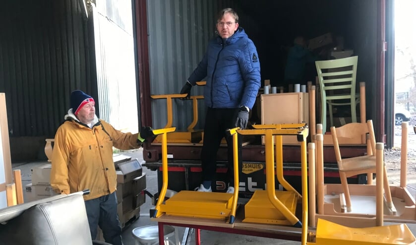 <p>Vrijwilligers laden schoolmeubeltjes in de container met hulpgoederen voor Suriname.</p>