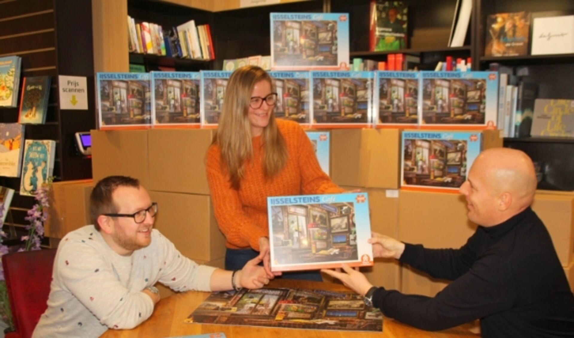Wouter Vermaat (rechts) ontvangt uit handen van Stephan en Melvienne Mulder van The Readshop de eerste IJsselsteinpuzzel: "We zijn wel klaar met voor de tv hangen." (Foto: Lysette Verwegen)