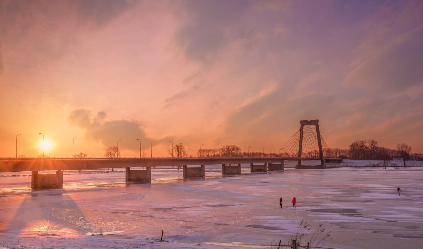 Deze foto is gemaakt op 12 februari bij zonsopkomst bij de Heusdense brug, ook de eerste schaatsers waren er al op het ijs te vinden. De lucht kleurde prachtig deze ochtend.