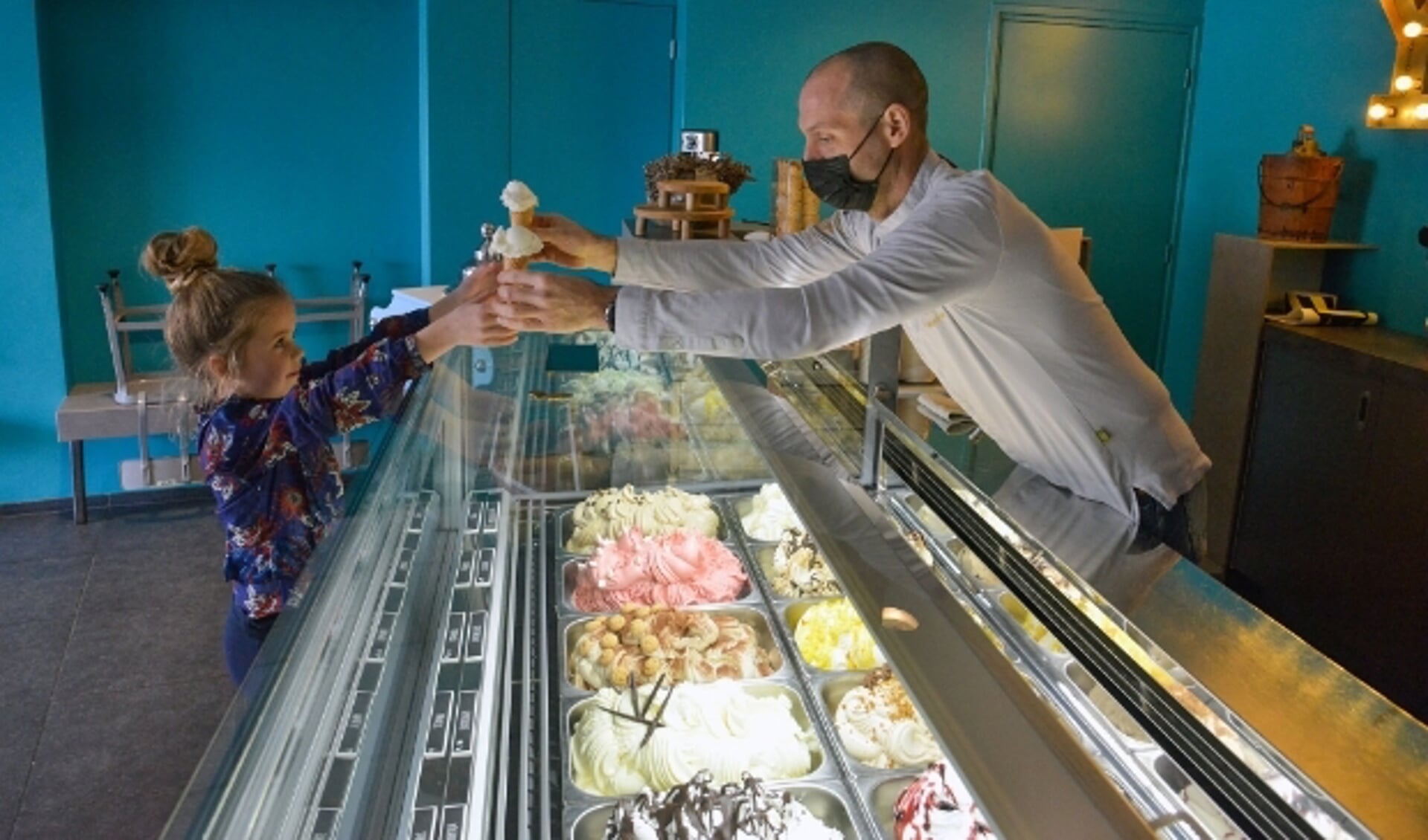 Tijdens de opening van Daan's Droomijs schept André Lammerse twee ijsjes voor buurmeisje Roos.   Foto: Paul van den Dungen