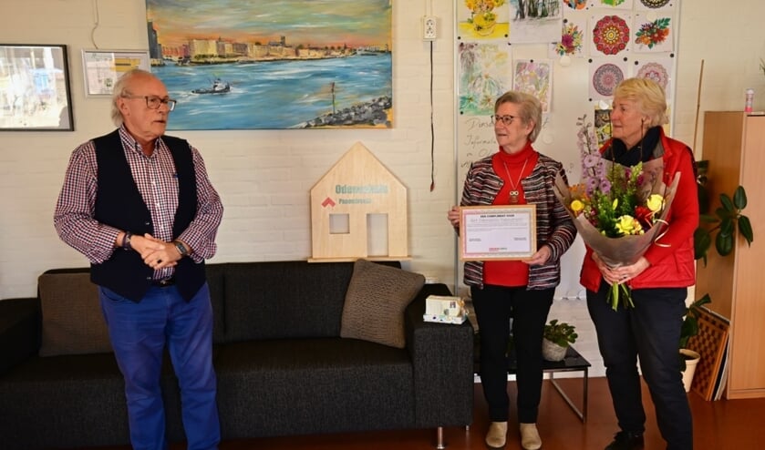 <p>• Leo Quist reikt het compliment uit aan twee vrijwilligers van het Odensehuis.</p>