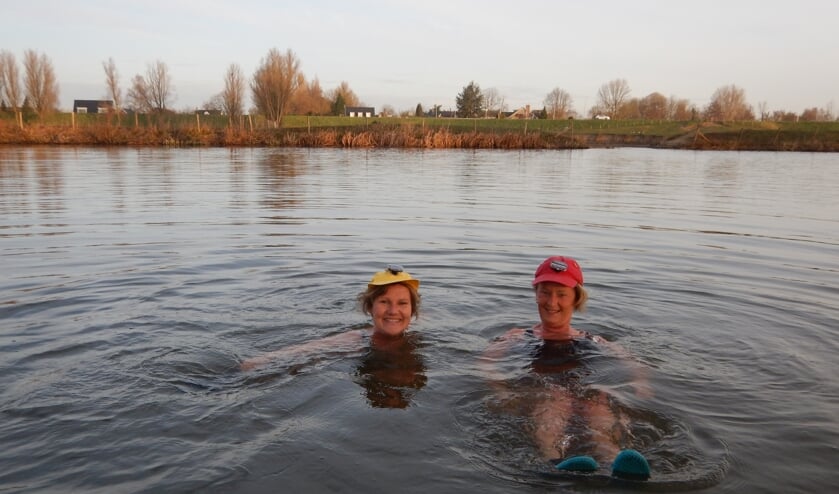 • Annemieke Kleen (l) en Pauline Vrij in het koude Lingewater met ‘verlichte’ pet voor de veiligheid.
