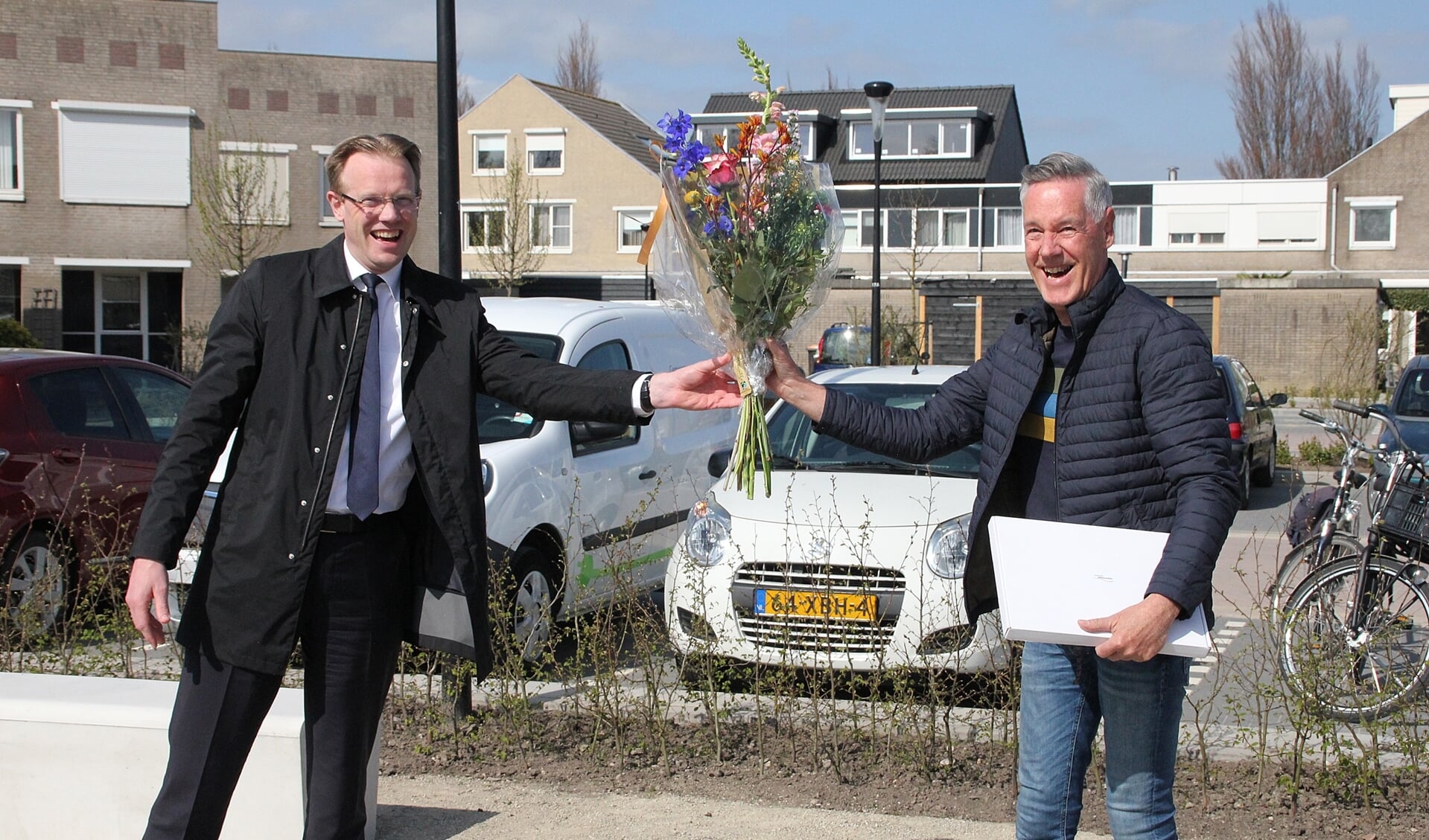 • Een cadeautje en bloemen van wethouder Peter Verheij (links) voor wijkgroeplid Ronald Vreeman.