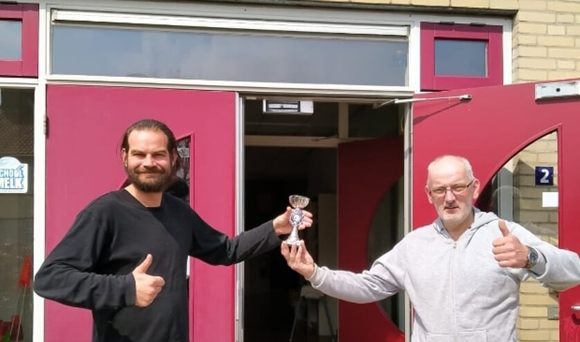 <p>Leerkracht Hans van Tussenbroek (links) neemt namen de leerlingen van basisschool Floriant de prijs van het Digitale Burgerweeshuis Jeugdschaaktoernooi 2021 in ontvangst van organisator Dirk van Zetten van Schaakvereniging RivierenlandScha</p>