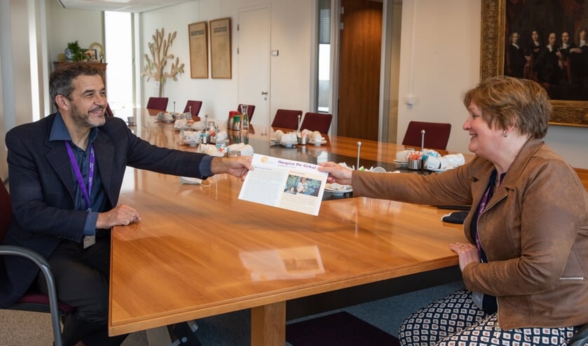 • Bestuurslid Heleen Roos van Hospice De Cirkel overhandigt de eerste jubileumjaarkrant aan ziekenhuisdirecteur Peter van der Meer.