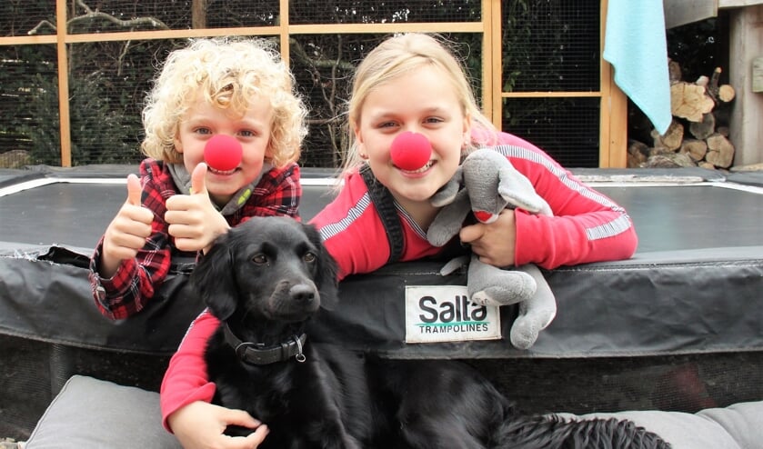 • Levi en Isa Hartmans met hun hondje op de trampoline.