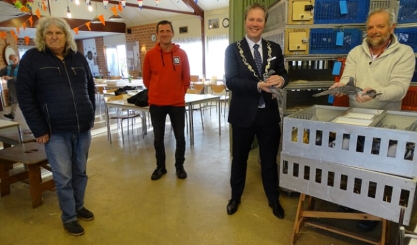 Tijdens het inkorven hield burgemeester de Vries met alle gemak een duif vast. Vlnr. Paul Satink, Paul Houdijk, Burgemeester de Vries en Gert den Houdijker