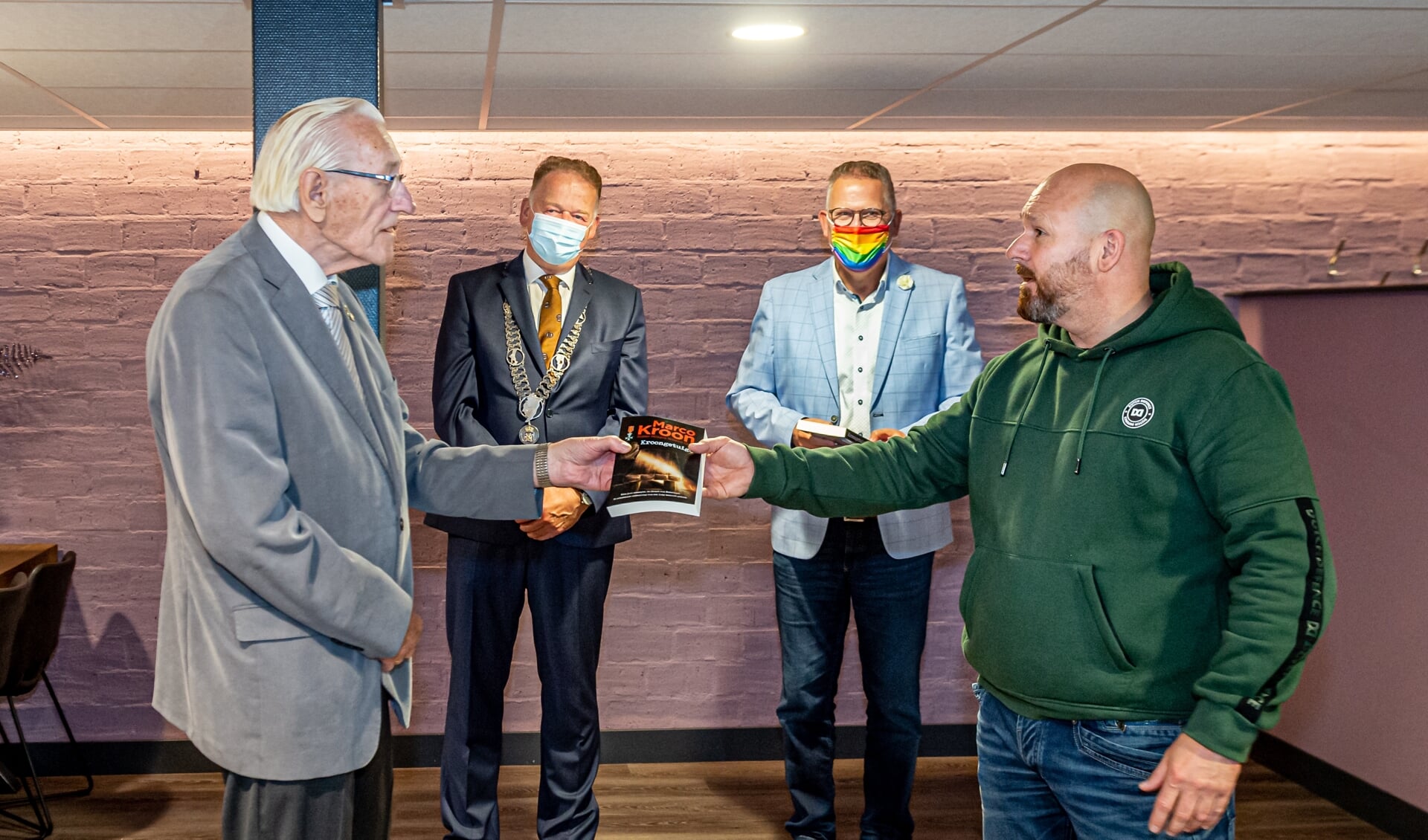 • Majoor Marco Kroon (rechts) reikt in Het Bastion te Schoonhoven zijn boek 'Kroongetuige' uit aan één van de aanwezige veteranen. 