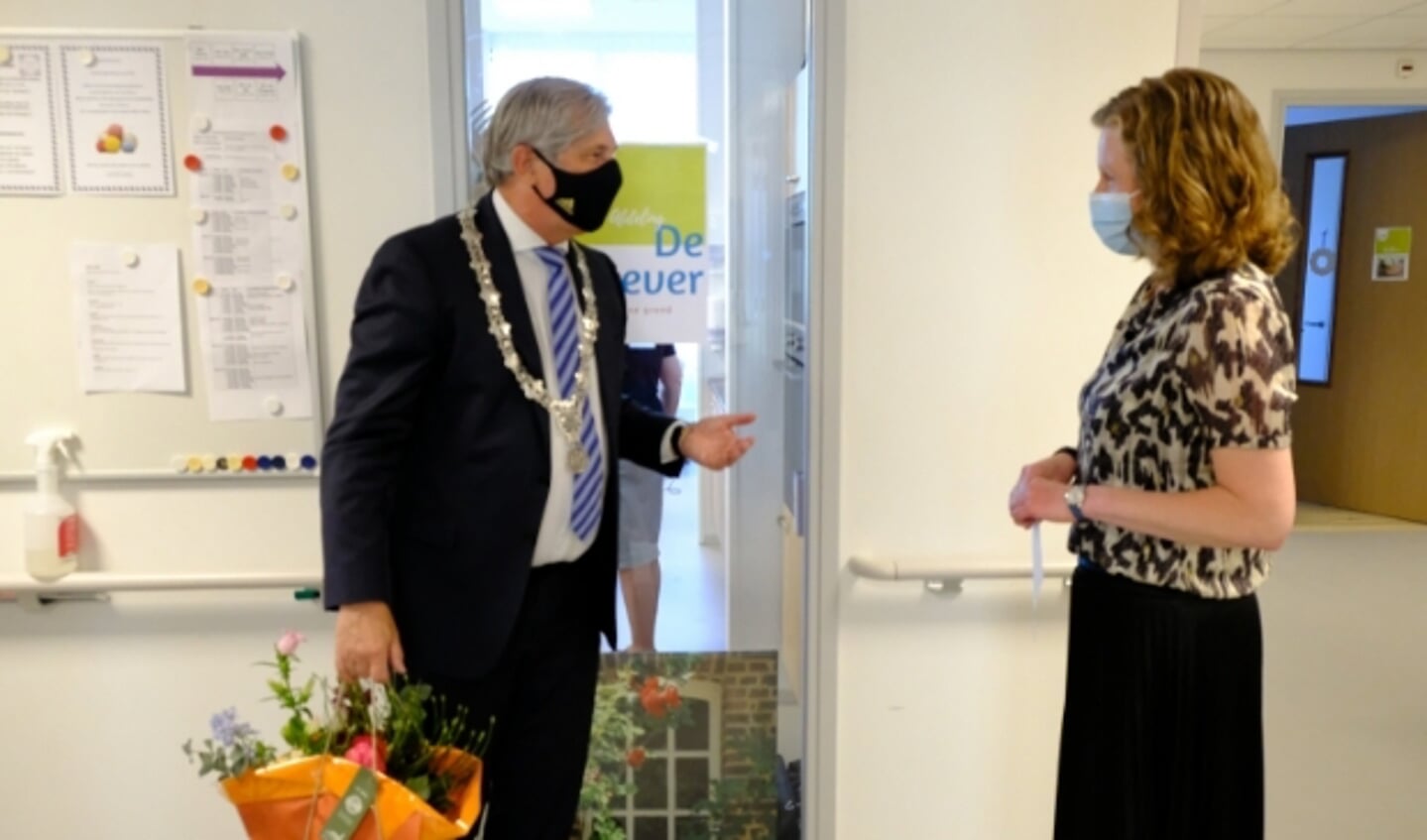 Burgemeester Peter Oskam in gesprek met locatiemanager Marianne de Vries, nadat hij een bos bloemen in ontvangst heeft genomen. 