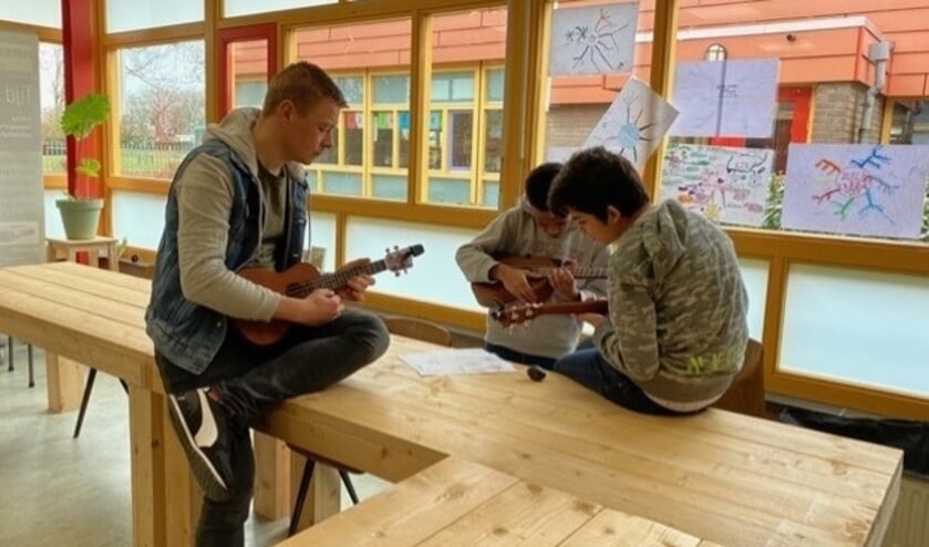 <p>Enkele kinderen van Petje Af Tiel met hun begeleider, op zondag, verdiept in een muzikale opdracht. </p>