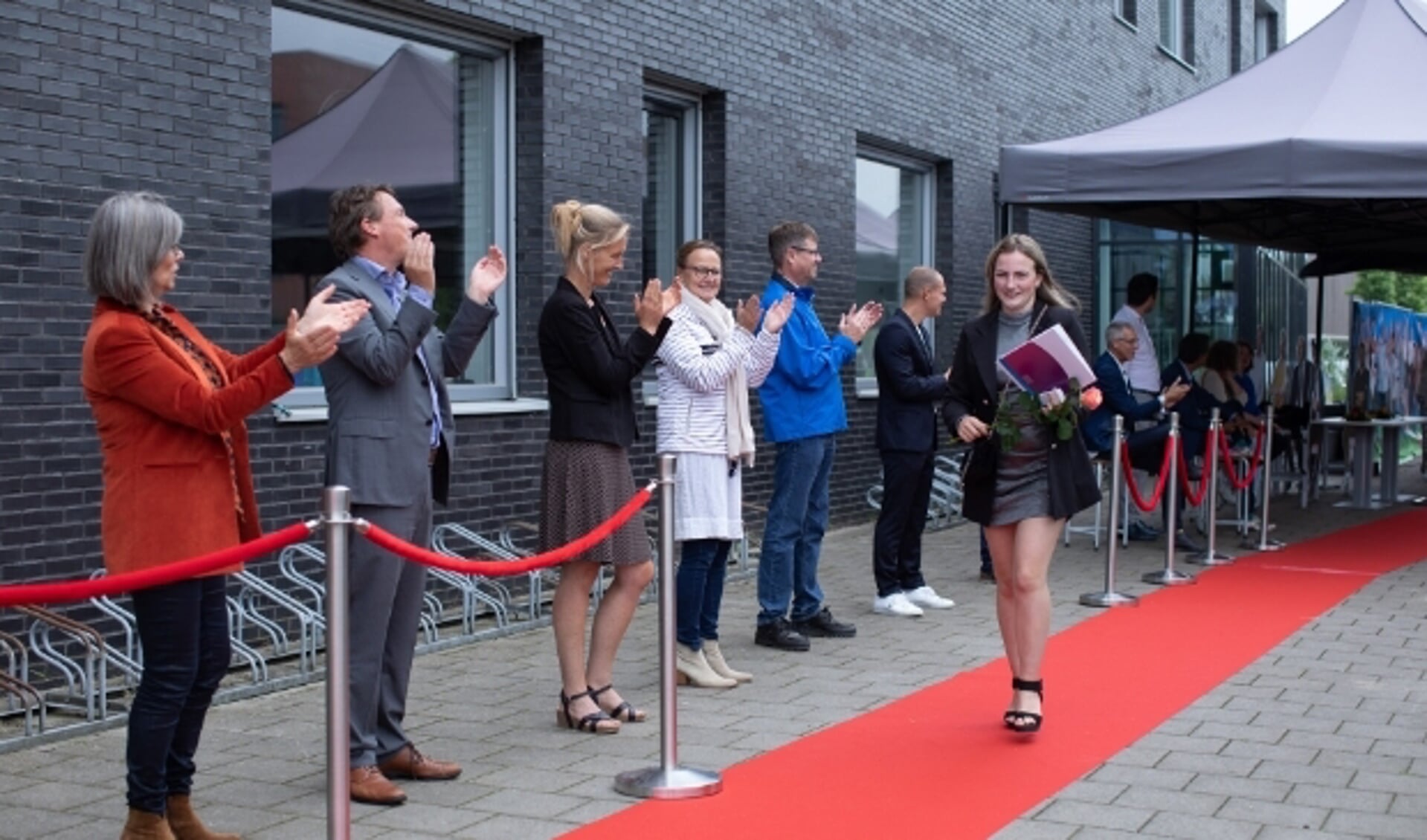 Fleur op de rode loper nadat ze onder luid applaus van havo-directeur Luuk van Beers (tweede van links) en zijn team haar diploma in ontvangst heeft genomen.