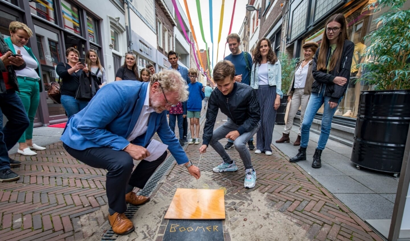 Tiel, 14 juli 2021
Voor het 5e jaar zijn de Woorden van de Tijd in de Tielse Weerstraat onthuld. Ongeveer 50 leerlingen met het (verplichte) vak CKV  van 4 Havo / VWO van het Lingecollege Lyceum hebben aan het project deel genomen. De winnende woorden en hun bedenkers zijn: ‘Simp’ van Manu Krishnadath (niet aanwezig), ‘Boomer’ van Mingus Termeer en ‘Corona’, ontworpen door Sofie van Rooij. Caro Agterberg, tevens bedenker van het project, Michiel van Luijn, maker van de tegels en Karin Eetgerink namens de gemeente Tiel vormden de jury. Wethouder Ben Brink mocht voor zijn 4e maal samen met de leerlingen de natuursteen tegels onthullen.
Foto Jan Bouwhuis.