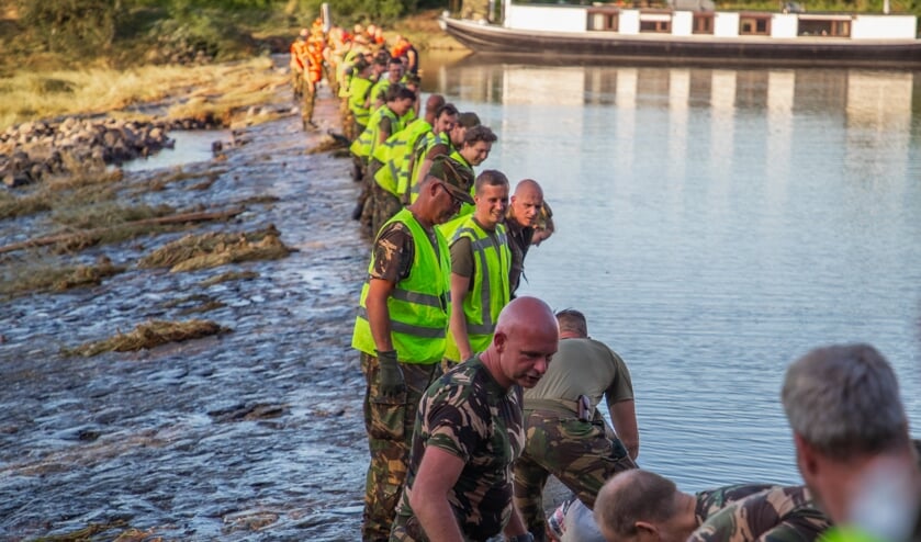 <p>• Met man en macht wordt gewerkt aan een waterafscheiding van zandzakken.</p>