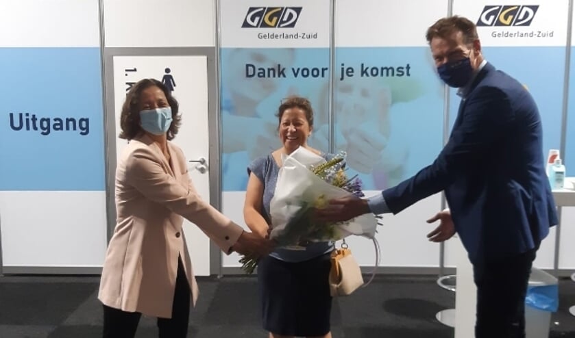<p>Natasja Lammers (midden) ontvangt de bloemen ter gelegenheid van 500.000e vaccinatie door de GGD Gelderland-Zuid.</p>