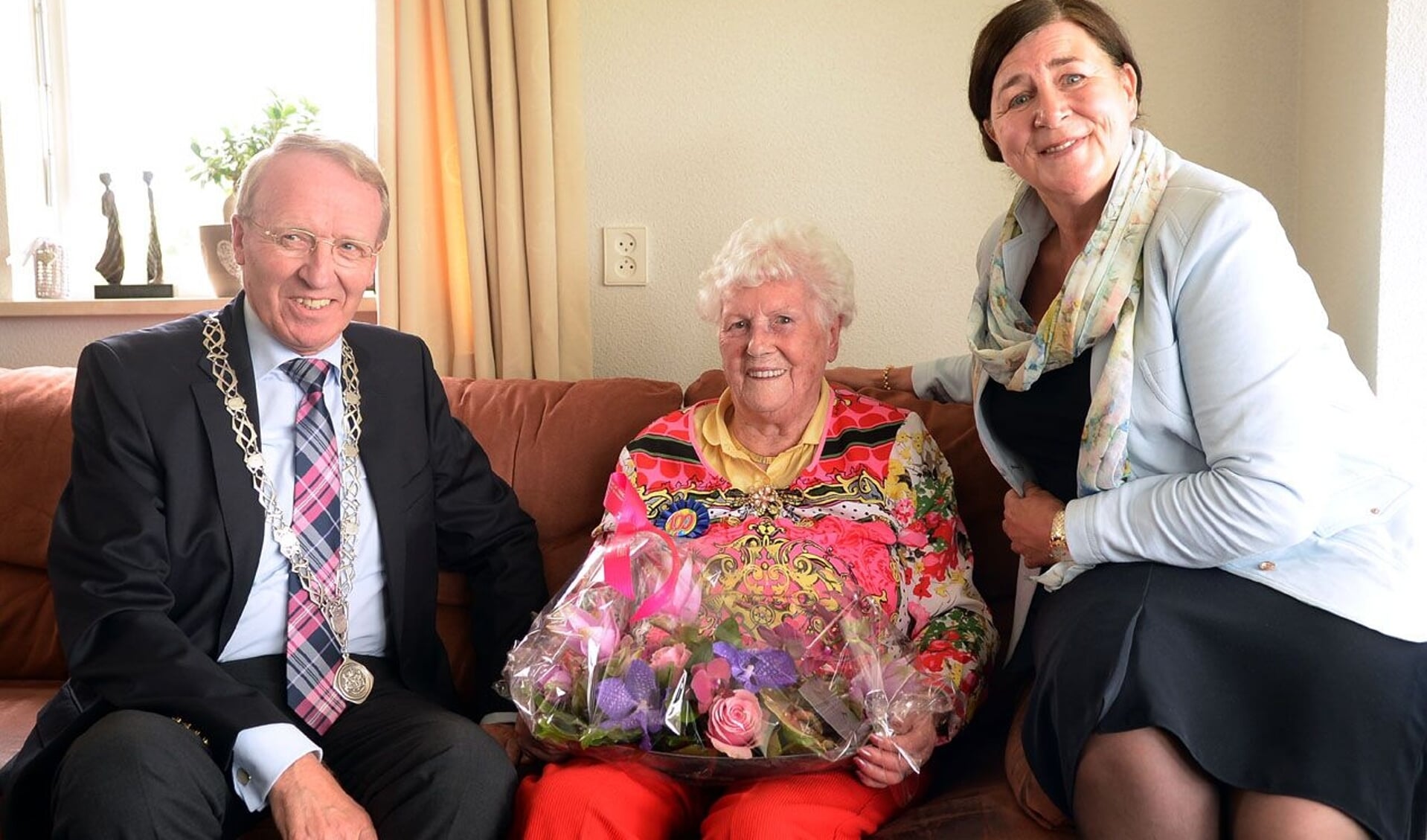 Elza Maria Schilder-Claeys op haar 100e verjaardag. Ze krijgt de felicitaties van burgemeester Arie Noordergraaf van de voormalige gemeente Woudrichem.