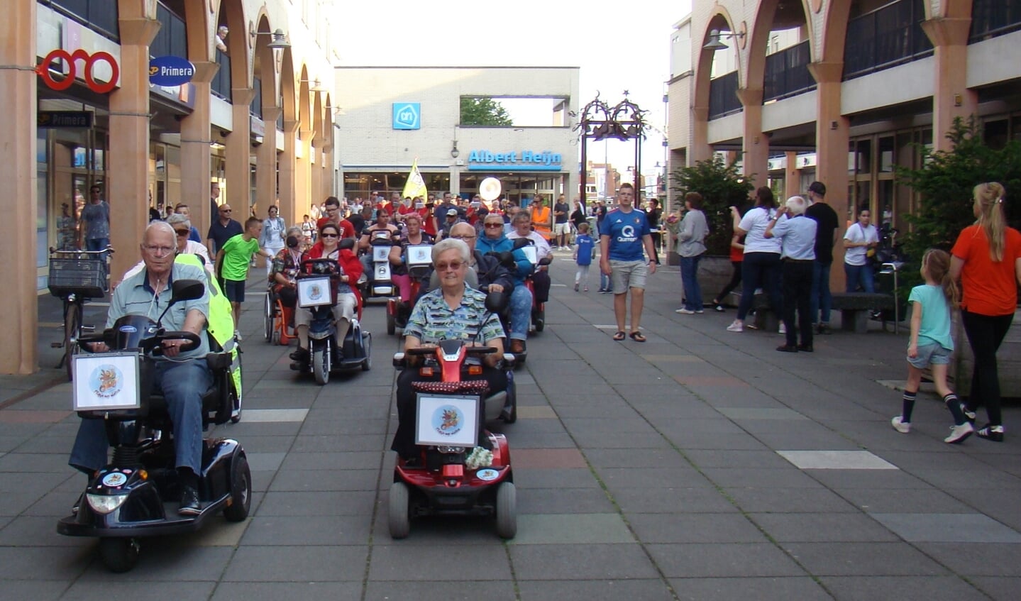 Scootmobielers van Flipje op Wielen rijden tijdens de avondvierdaagse winkelcentrum Passewaaij binnen.