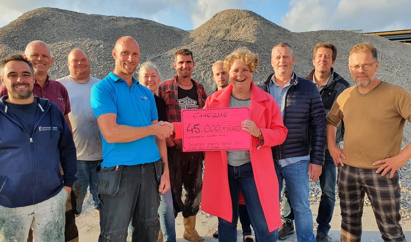 • Met de puin als achtergrond reikt Renata de Groot de cheque uit aan Kees-Jan de Haay, één van de door de brand getroffen ondernemers. (foto: Jan Timmer)