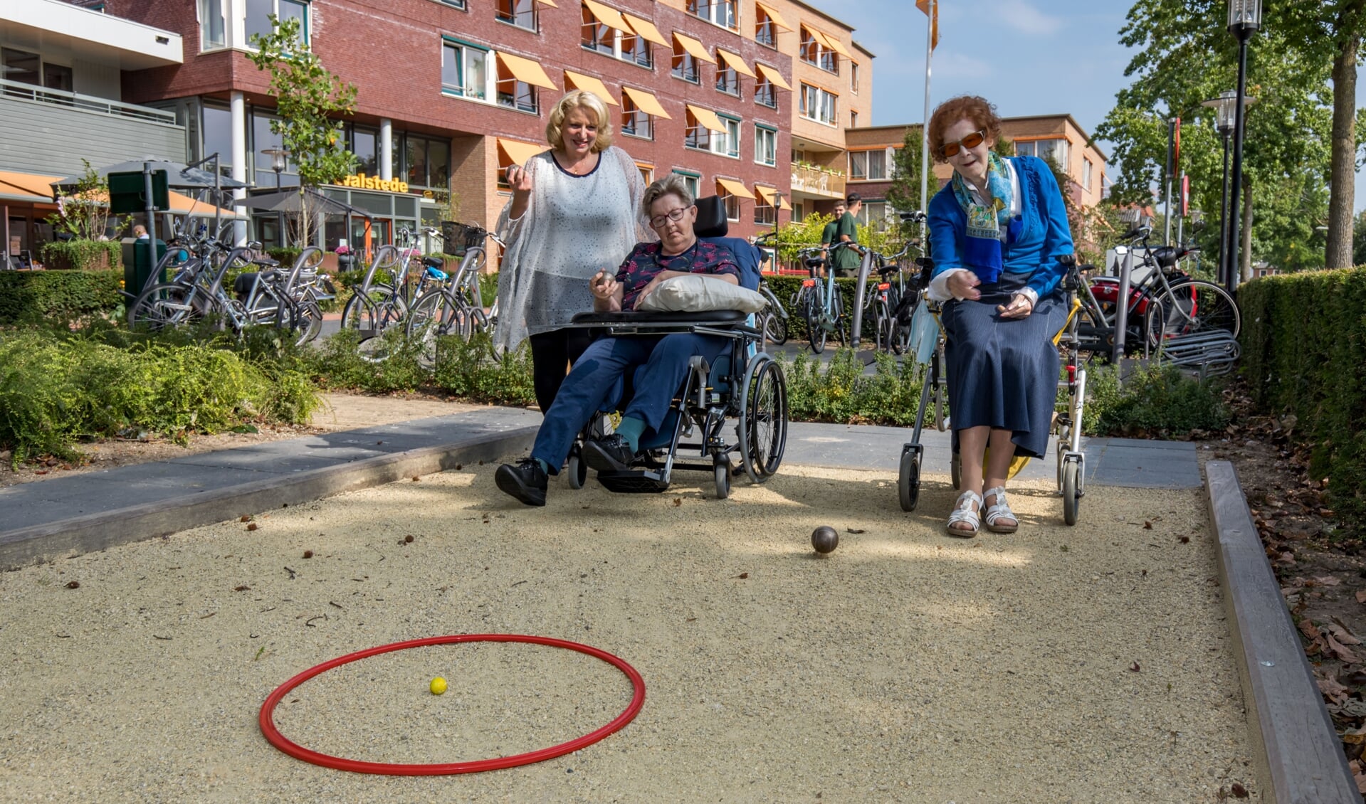Welzijnsmedewerker Natascha van Empel begeleidt bewoners van Woonzorgcentrum Walstede bij hun balspel op het jeu de boules-baantje.