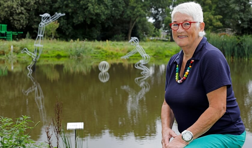 • Kunstenaar Saskia Fluks, met achter haar het door haar gemaakte kunstwerk in de vijver.