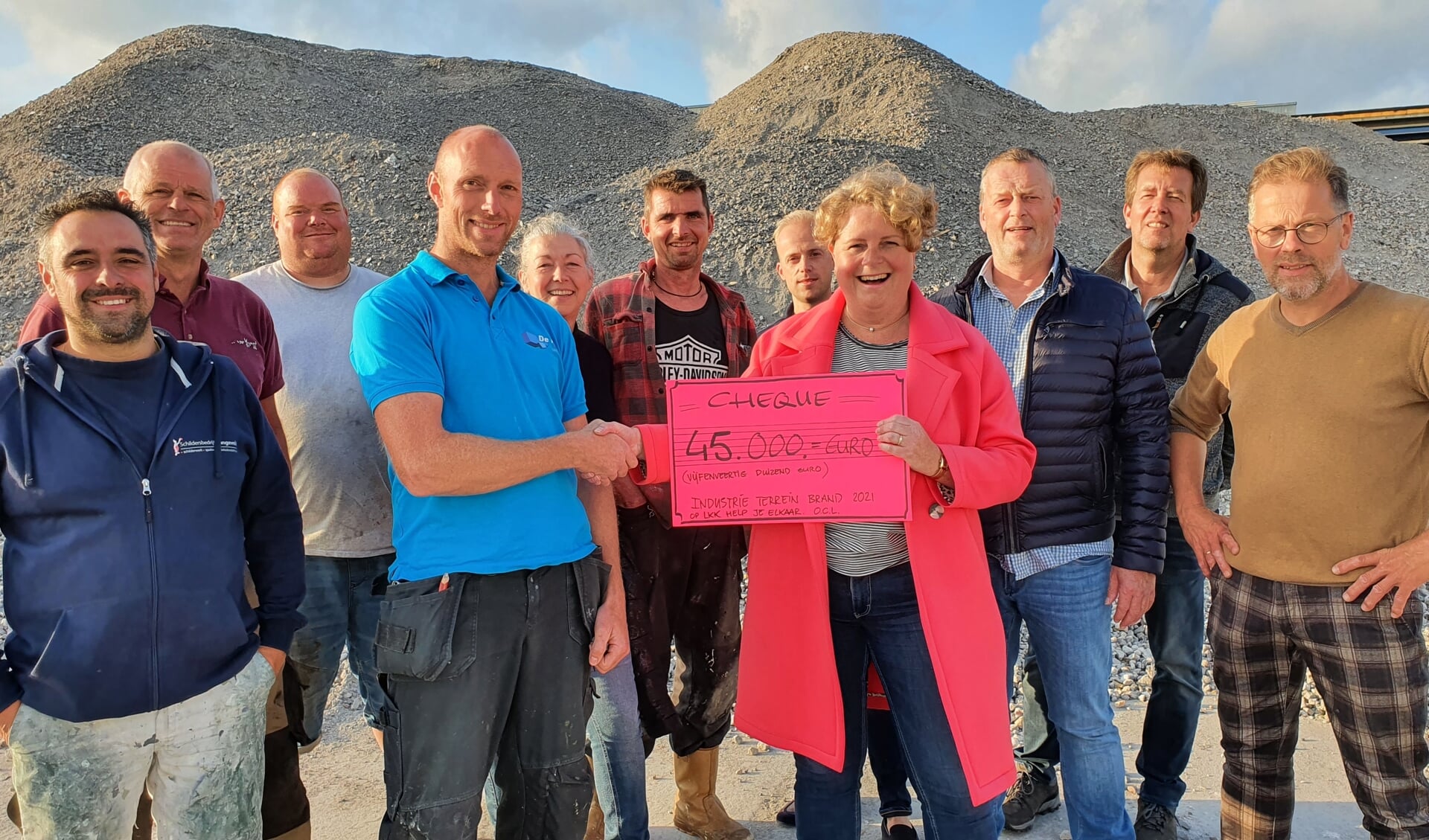 • Met de puin als achtergrond reikt Renata de Groot de cheque uit aan Kees-Jan de Haay, één van de door de brand getroffen ondernemers. (foto: Jan Timmer)