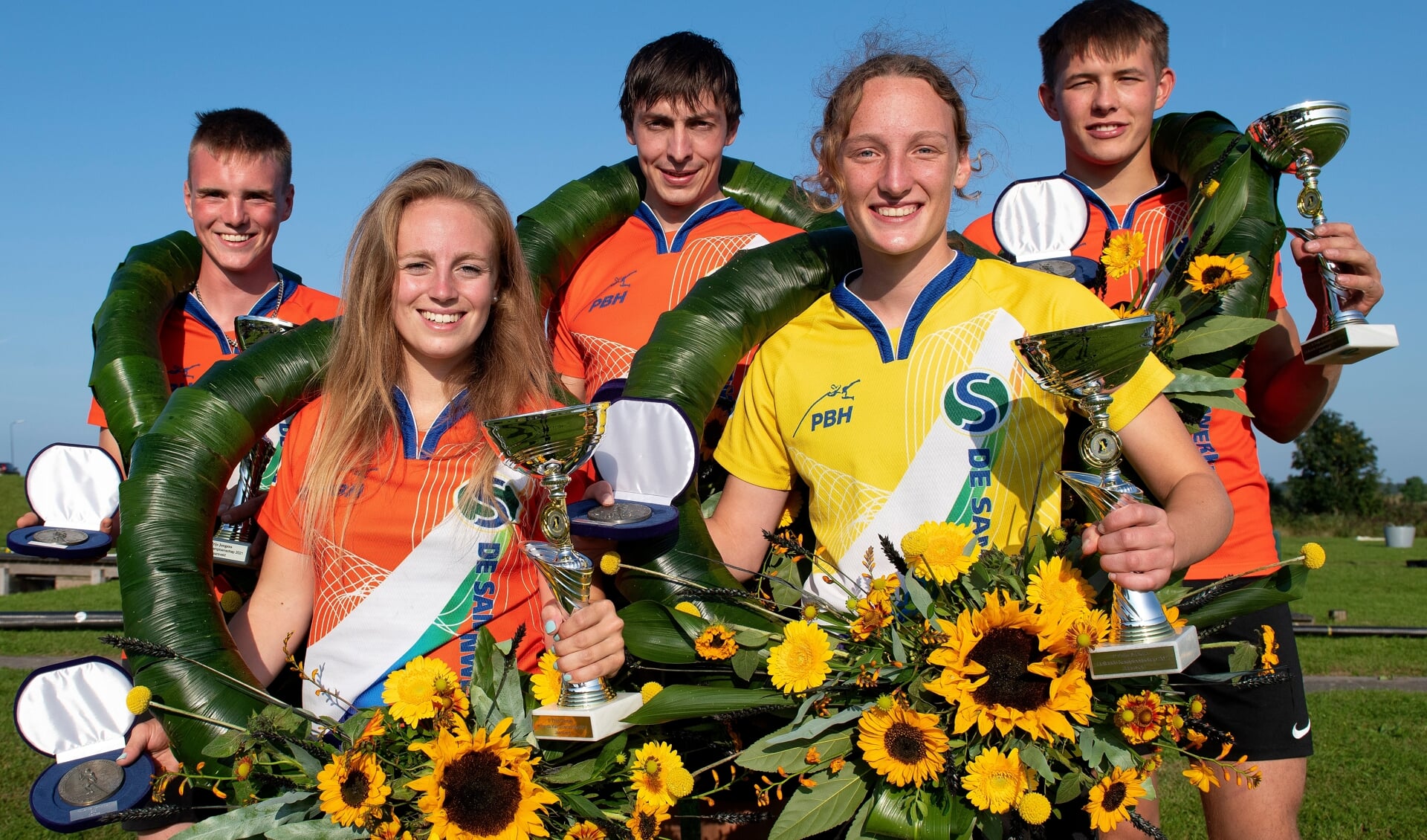 De winnaars van het Hollands Kampioenschap. Met lauwerkransen, bekers en zonnebloemen.