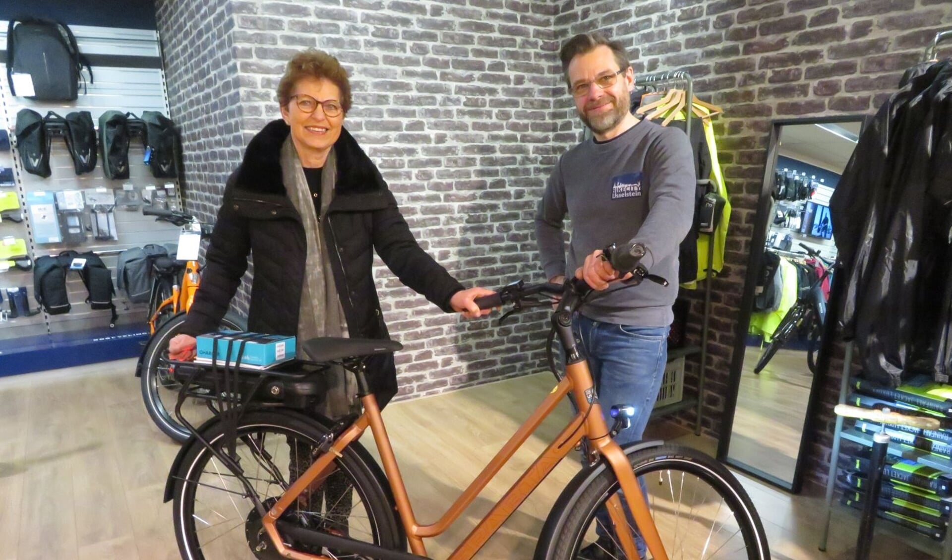 Eigenaar Peter de Bie van BikeCity overhandigt de hoofdprijs, een e-bike, aan Pien Breedveld.