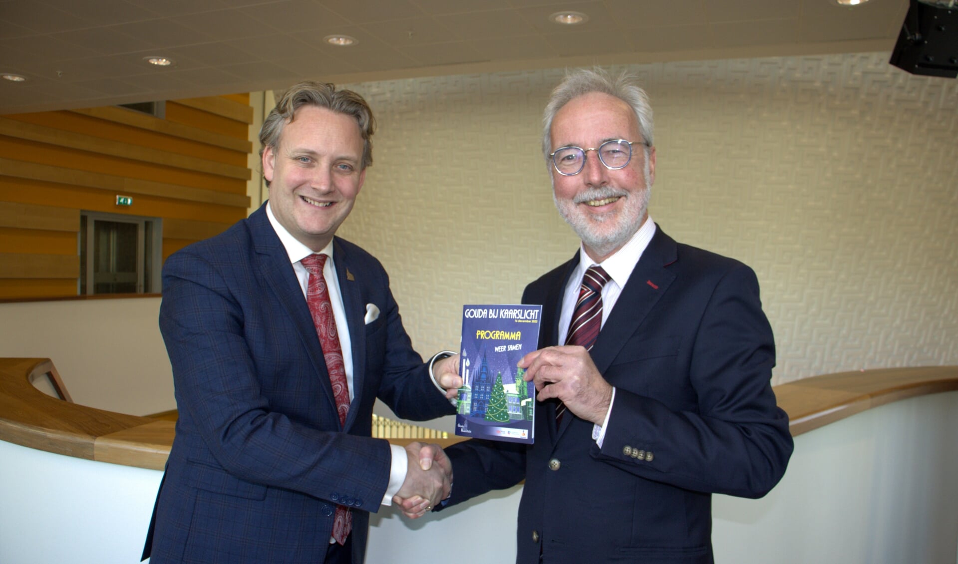 Burgemeester Pieter Verhoeve ontving vanmiddag het eerste programmaboekje van Paul Buis, voorzitter van stichting Gouda bij Kaarslicht.