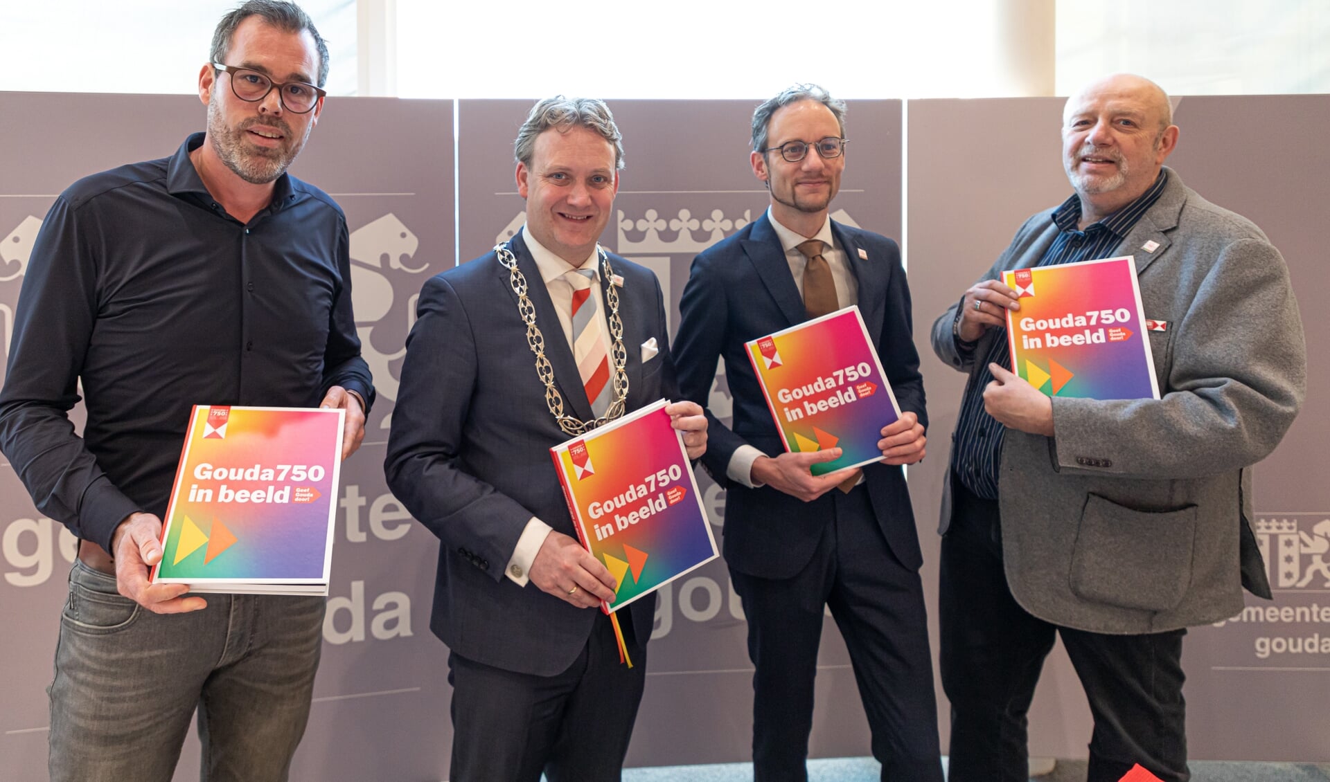 Marien Brand, burgemeester Pieter Verhoeve, wethouder Thierry van Vugt en Ronald van Rossum met het boek. 