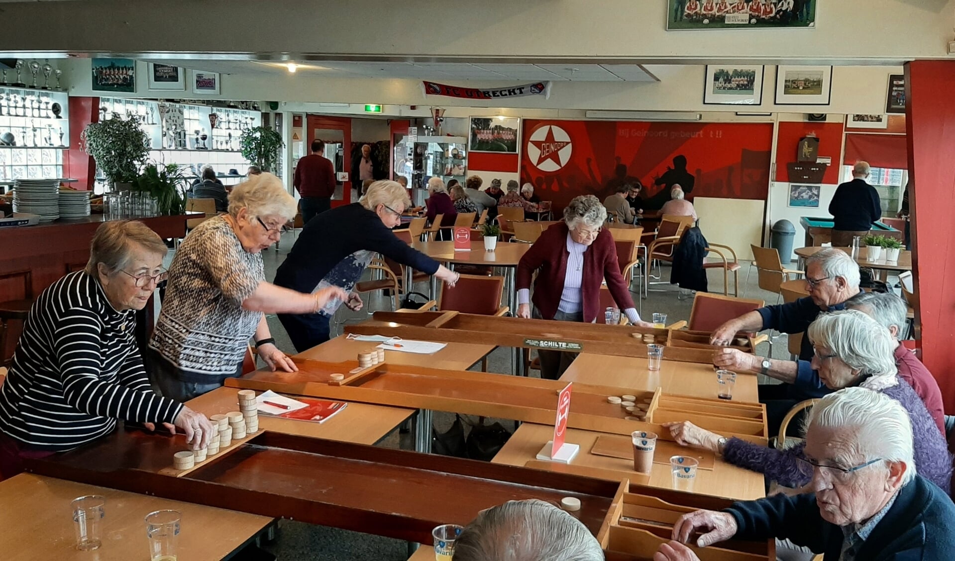 Ouderen zijn aan het sjoelen tijdens 'Geinoord Met En Voor Elkaar' in de kantine van SV Geinoord.