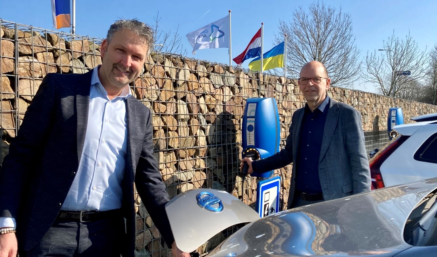 • Wethouders Roland van Vugt en Hans Tanis, bij laadpalen op het parkeerterrein van gemeente Altena.