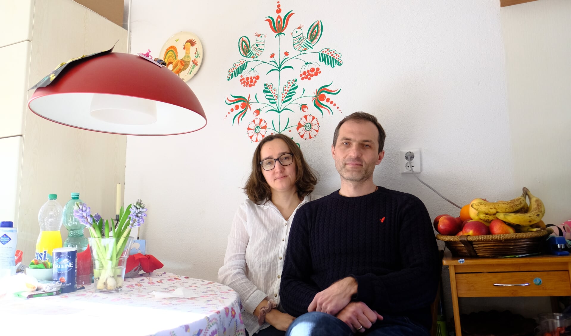 • Nataliya en Dmytri Galagan, met achter hen een zelf geschilderde familieboom in Oekraïense stijl.