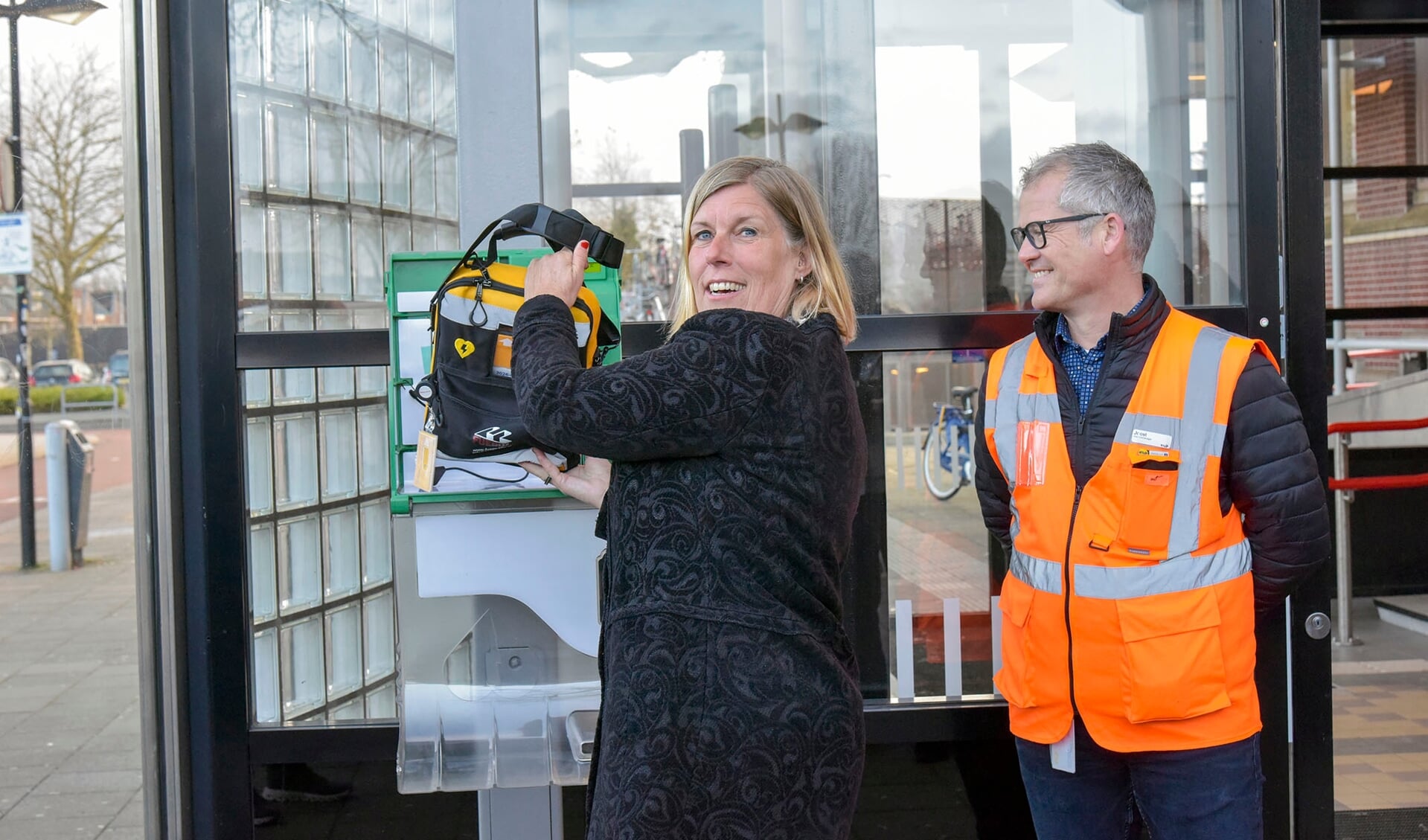 • Ans Rietstra, lid van de Raad van Bestuur van spoorbeheerder ProRail, laat de nieuwe AED op Station Woerden zien. 