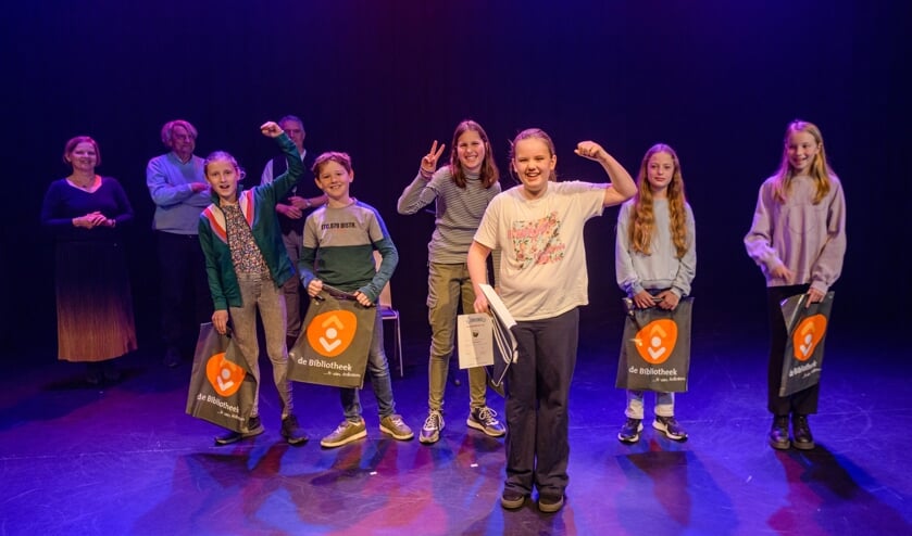 <p>Op de voorgrond van links naar rechts de voorlezers Evi, Hidde, Zara, Laura, Fem en Noa, op de achtergrond de jury.</p>