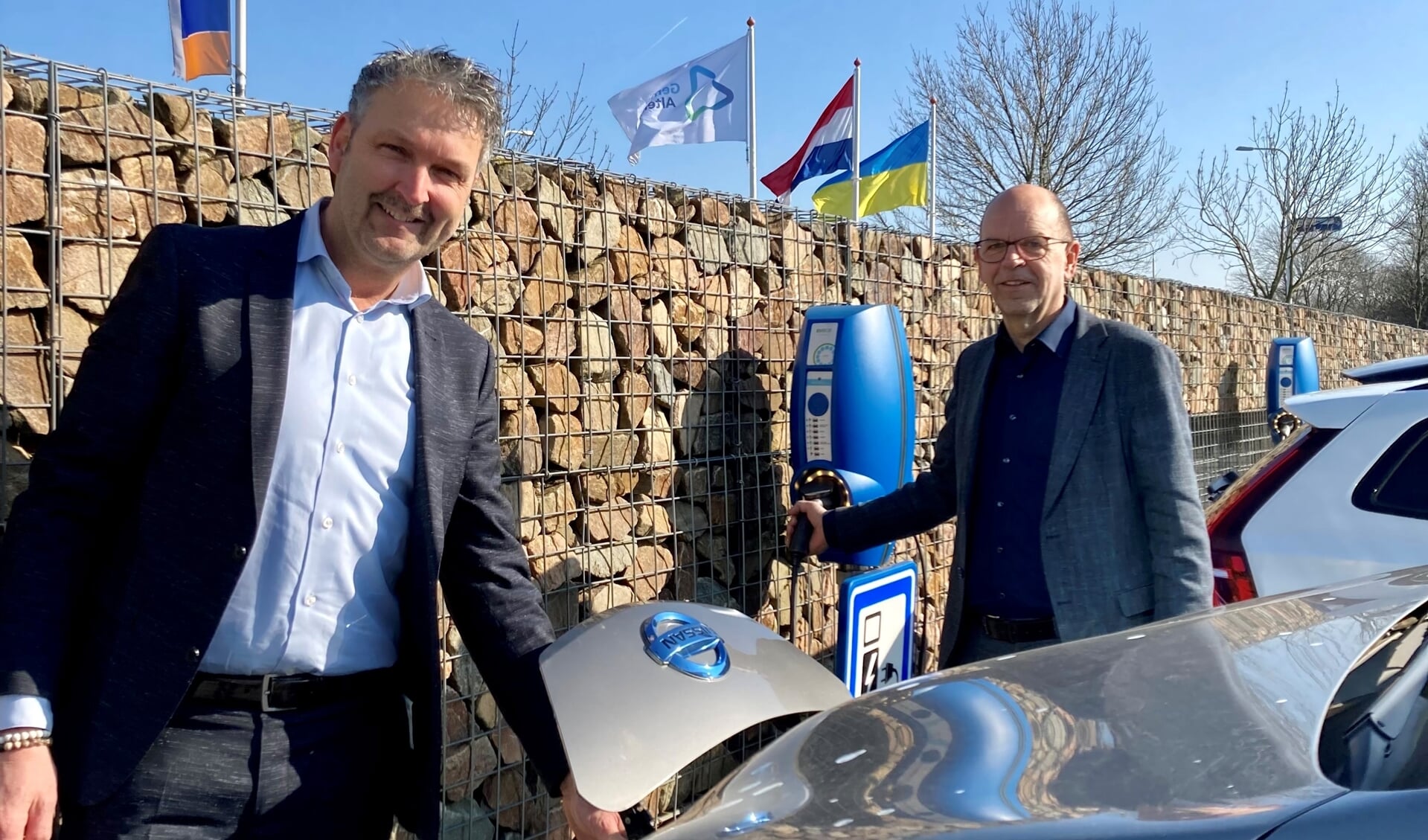 • Wethouders Roland van Vugt en Hans Tanis, bij laadpalen op het parkeerterrein van gemeente Altena.