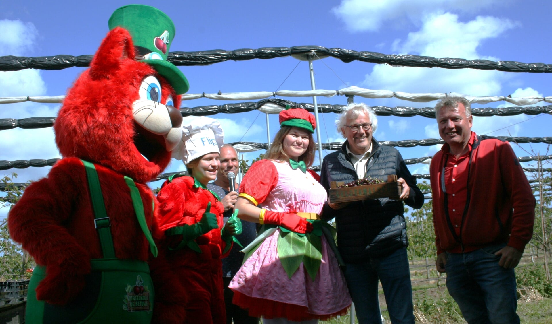 • Te midden van Cherrycat, fruitbaasje Flipje, kersenmeisje Lieke en Aart Blom neemt Gerrit van Leeuwen zijn kistje kersen in ontvangst.