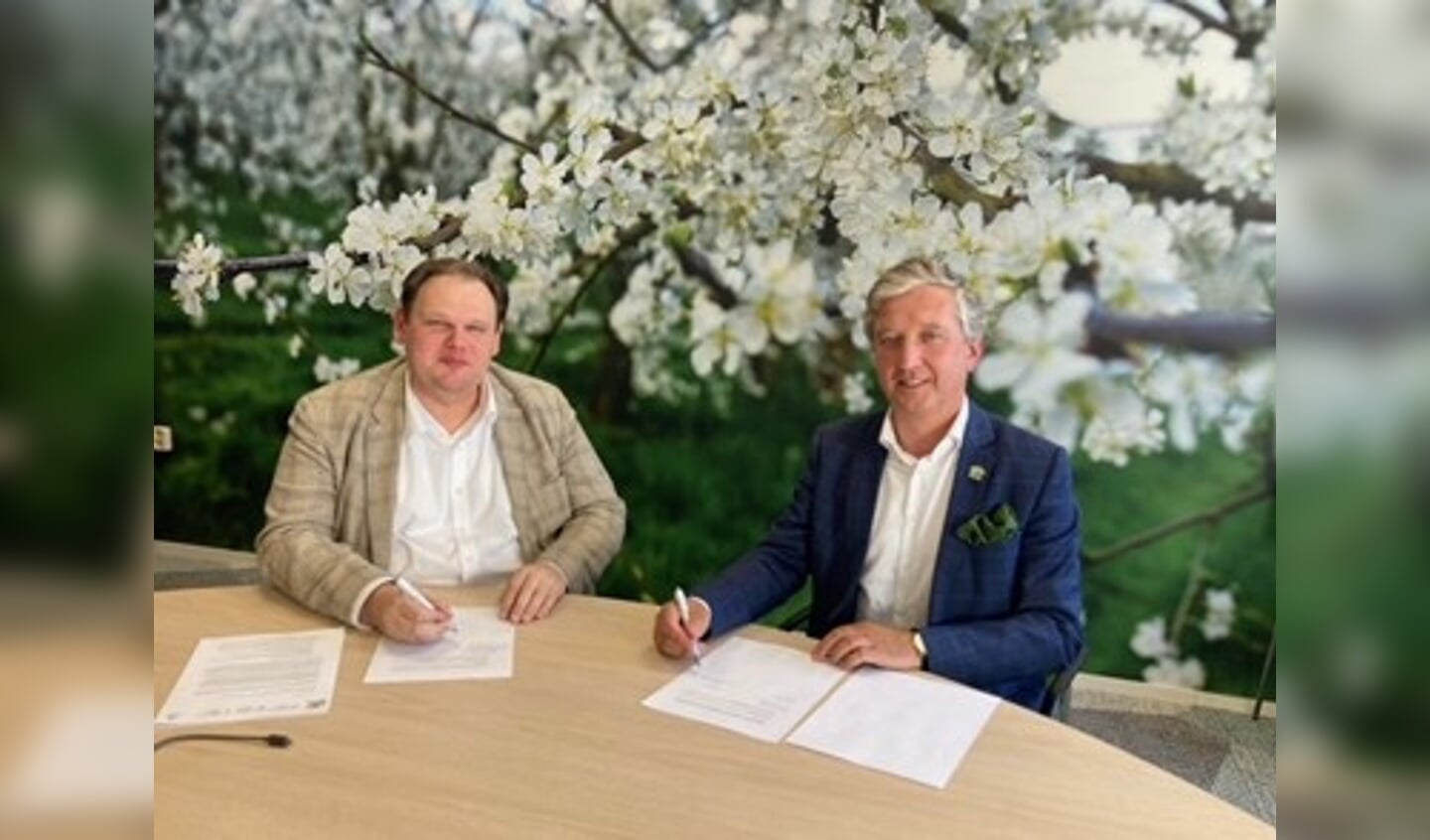 Hans Beenhakker van FruitDelta Rivierenland (rechts) en Laurens Verspuij namens Fruitcorso ondertekenen het contract 