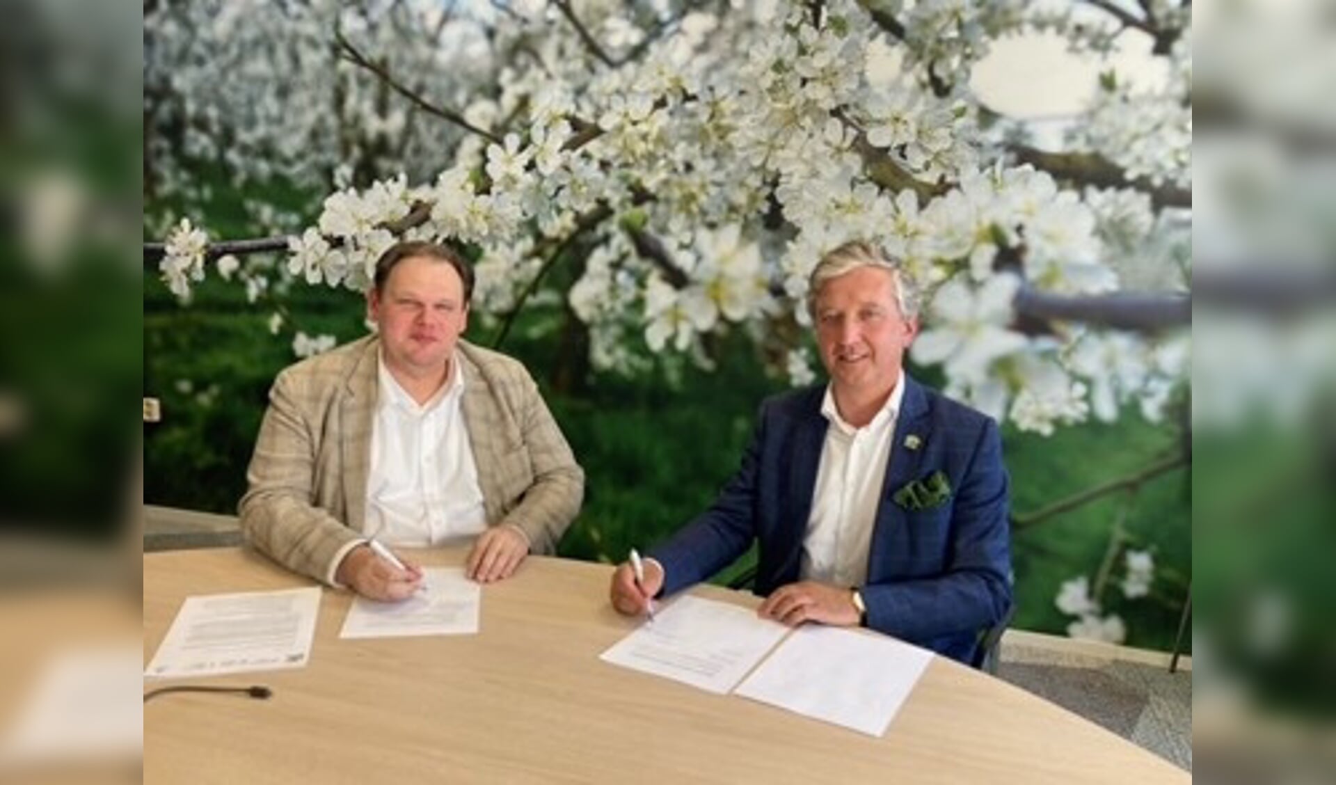 Hans Beenhakker van FruitDelta Rivierenland (rechts) en Laurens Verspuij namens Fruitcorso ondertekenen het contract 