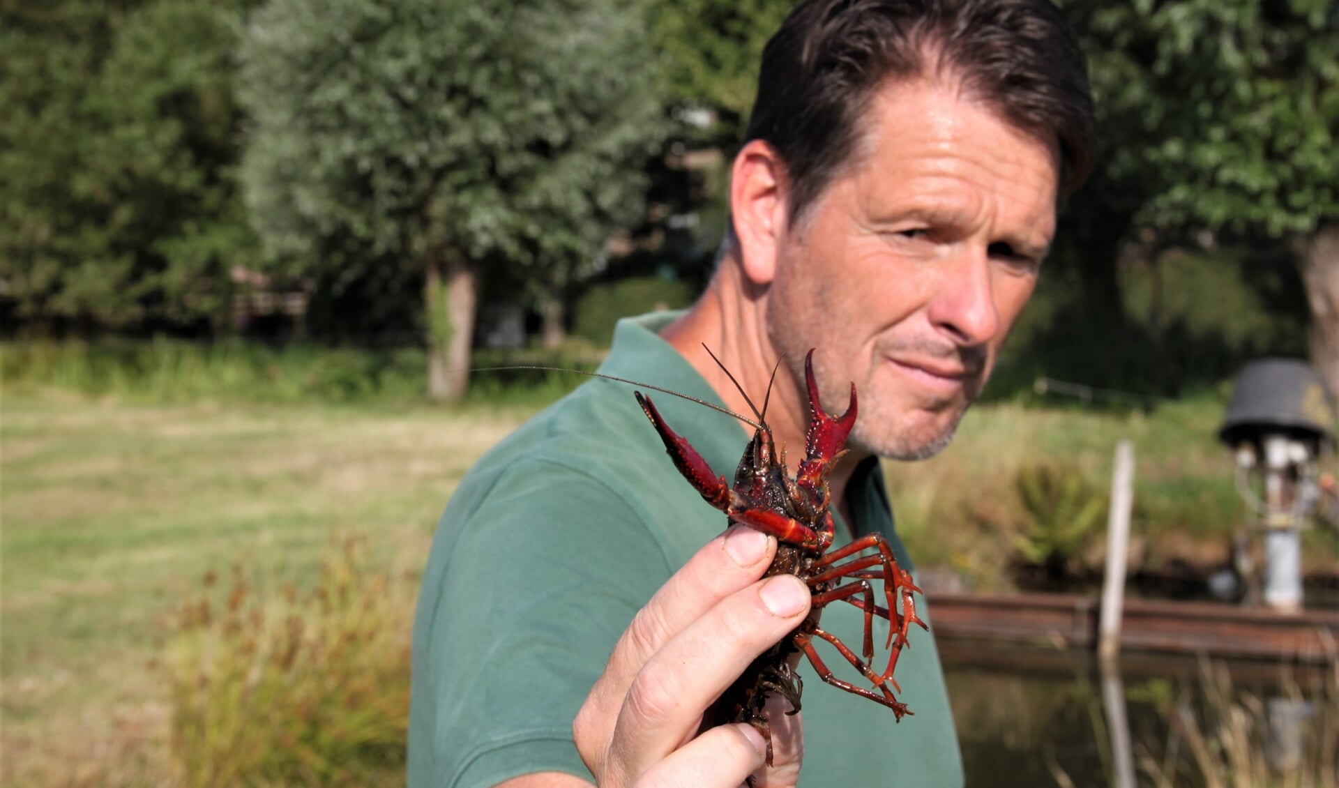 • Onderzoeker Fabrice Ottburg met in zijn hand een rode Amerikaanse rivierkreeft.