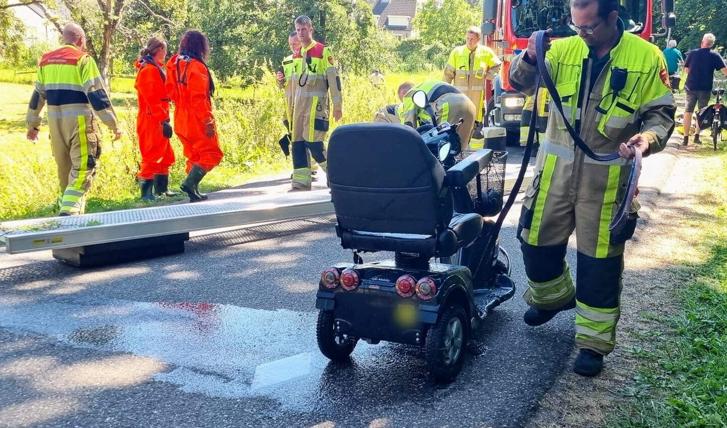 • De brandweer hielp de doorweekte man en zijn kletsnatte scootmobiel op het droge.
