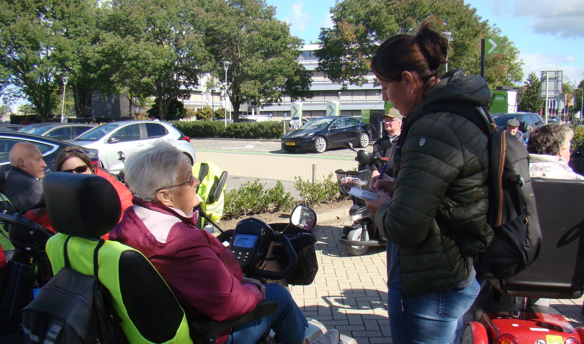  Drukte op de parkeerplaats bij Van der Valk, terwijl de verslaggeefster van Omroep Gelderland in gesprek is met deelnemers van Flipje op wielen