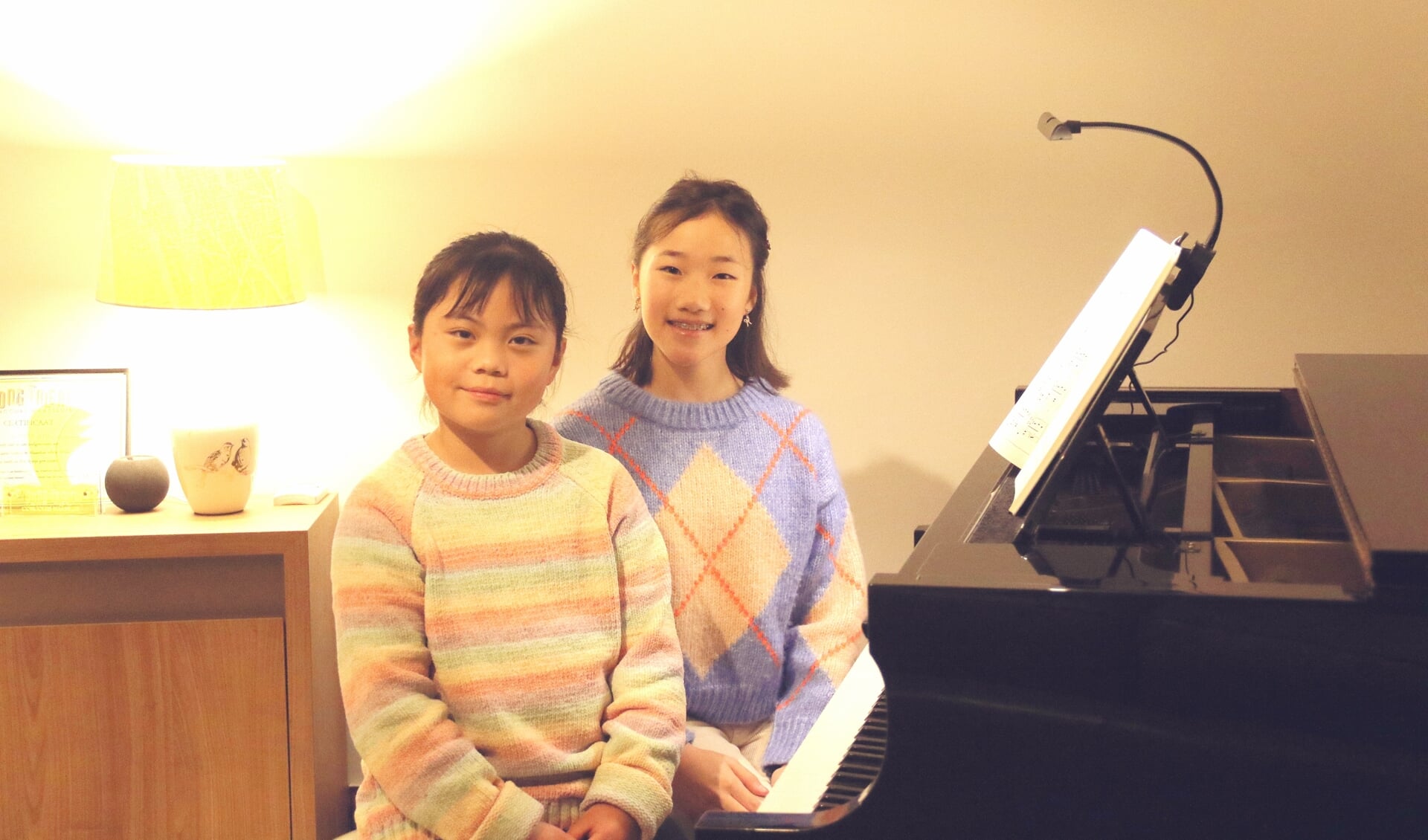 • Lingyi (links) en Yuewen op de plek waar zij zich thuis voelen: achter de piano.