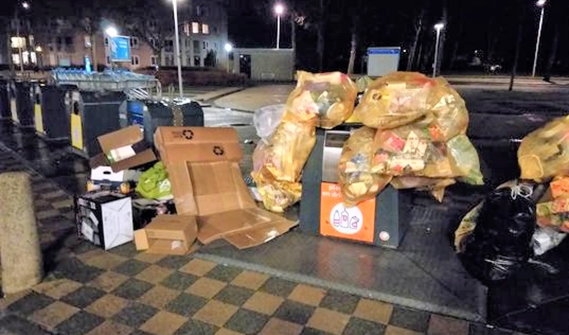 • Stapels zakken bij de afvalcontainers bij winkelcentrum Wilgendonk.